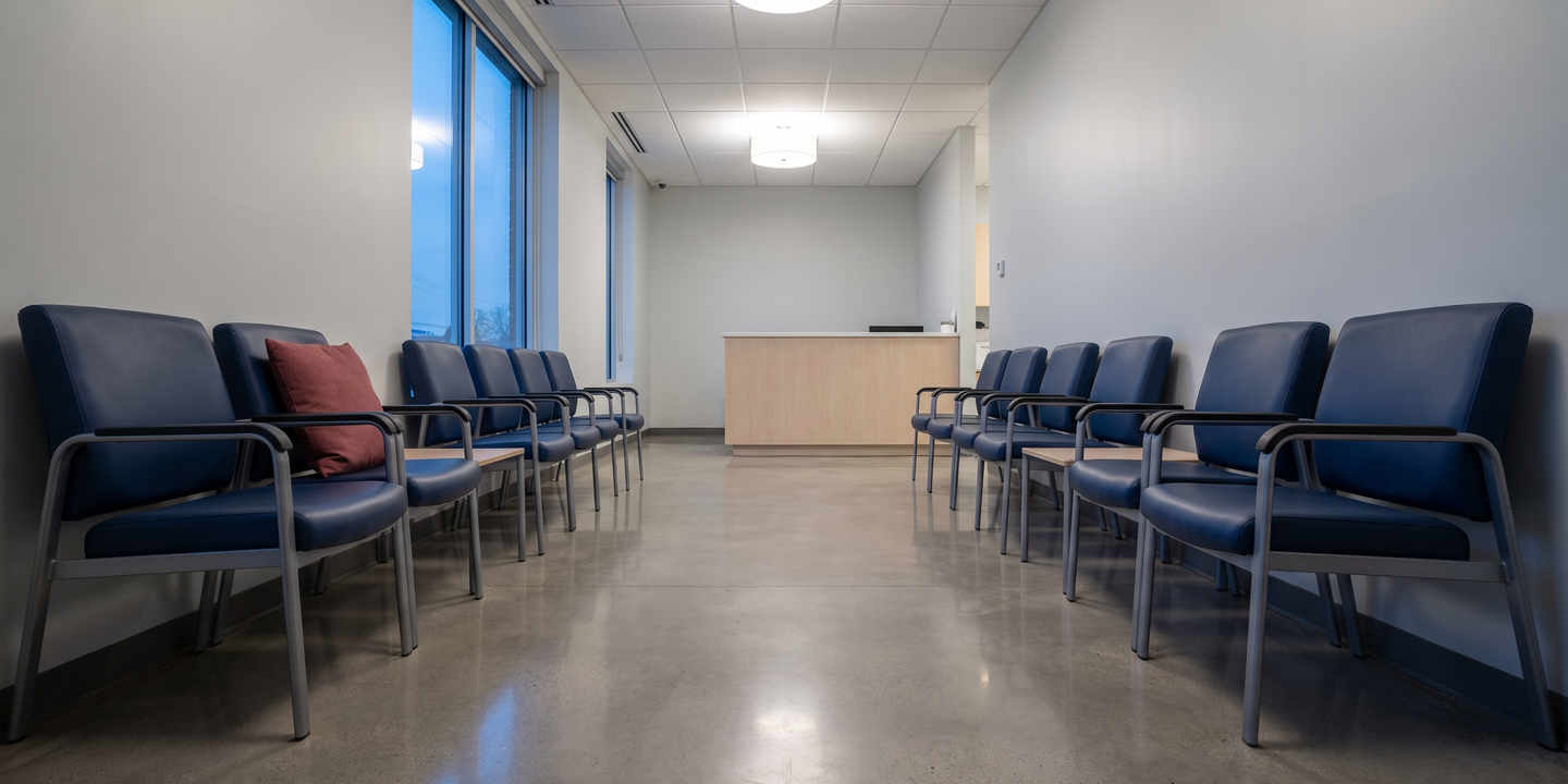 An empty clinic waiting room with vinyl seating and a reception counter after hours.